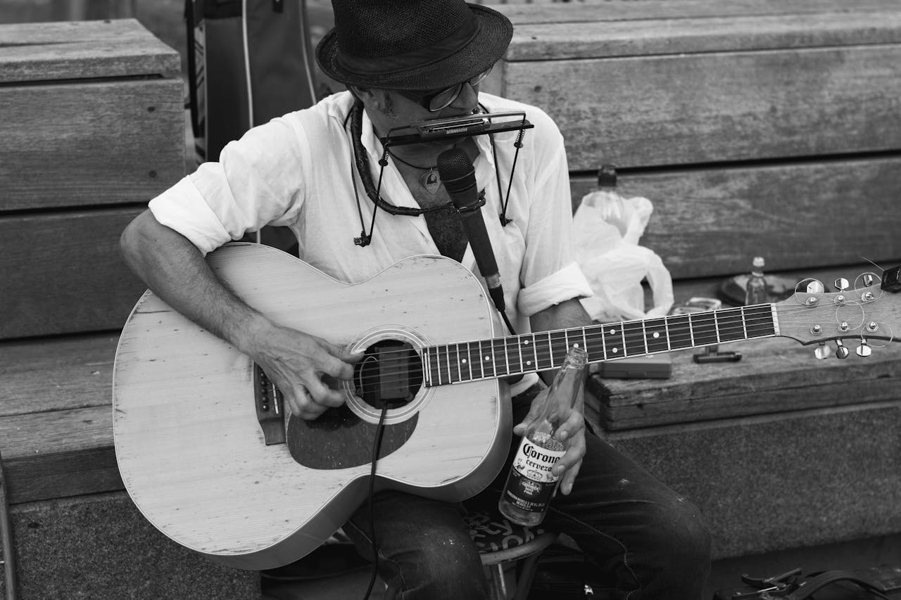 Black and white photo of a street musician playing an acoustic guitar.