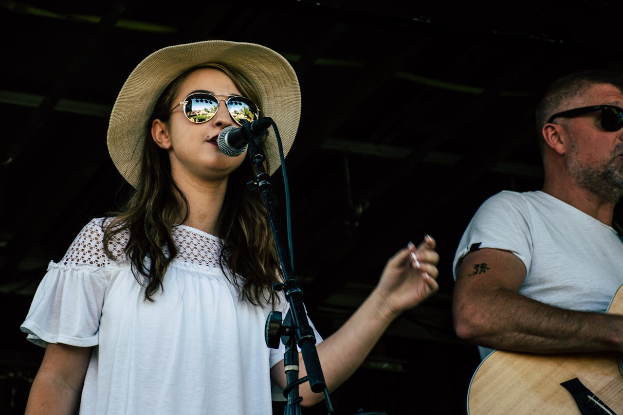 A vibrant outdoor concert featuring a female singer and male guitarist performing passionately on stage.